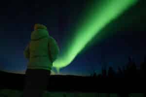 SBT guide Harrison captured this image in March 2026 on tour of a guest looking out at a green band of aurora borealis from outside of Fairbanks at a private aurora viewing location.